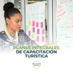 Planes integrales de capacitación turística Mujer señalando un tablero con notas adhesivas y esquemas, representando planificación y capacitación en el sector turístico.